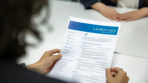 A printed CV being reviewed across a desk